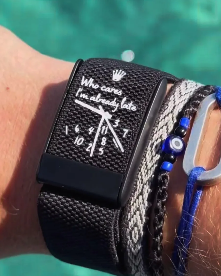 A black woven wearable band with a handwritten clock design and short text