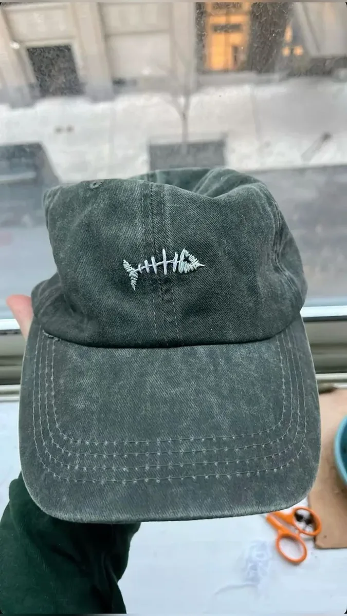 A pale fishbone design embroidered on a washed green cap